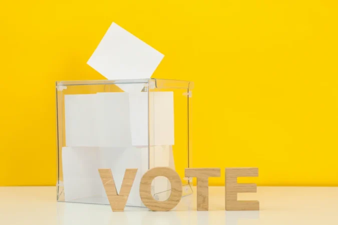 voting-box-with-bulletins-and-text-vote-on-yellow-2023-11-27-05-29-21-utc Vote